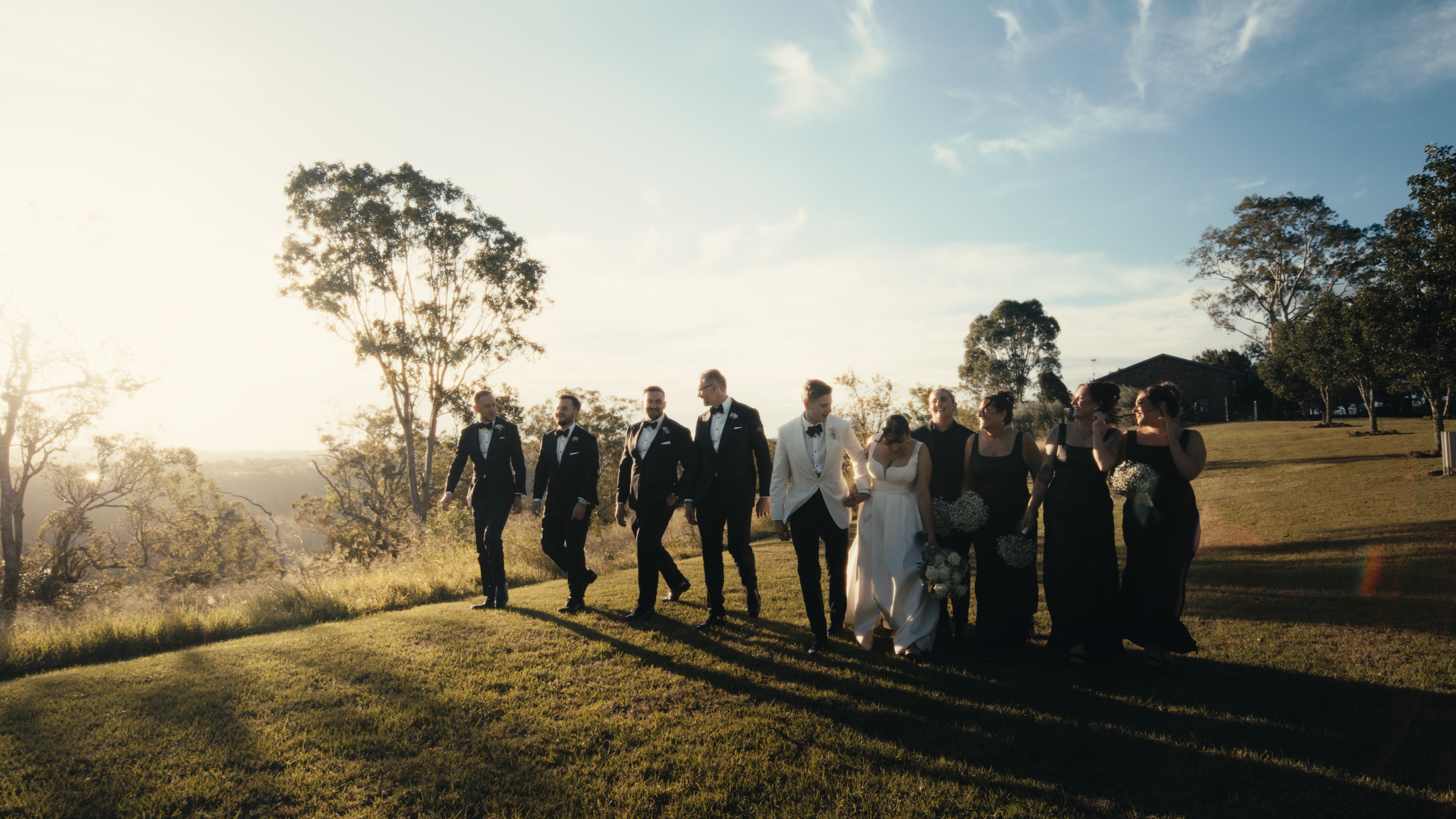 Wedding videography in Queensland with wedding party on hillside at sunset